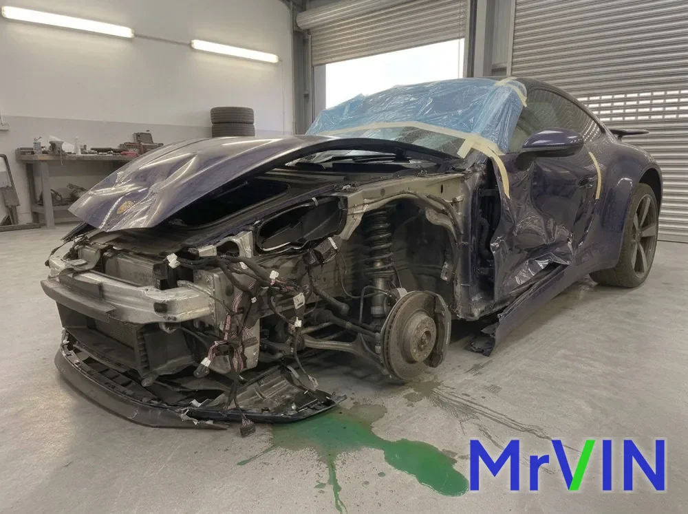 A dark blue Porsche 911 with its front end torn open in a body shop