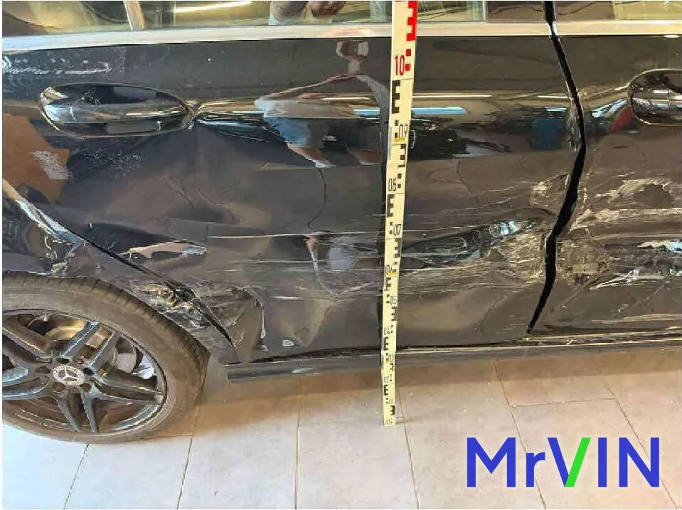 An insurance assessor measuring side damage on a Mercedes A-Class