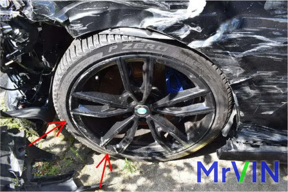 The front wheel of the BMW M340d pushed back into its arch, marked with the assessor's red arrows