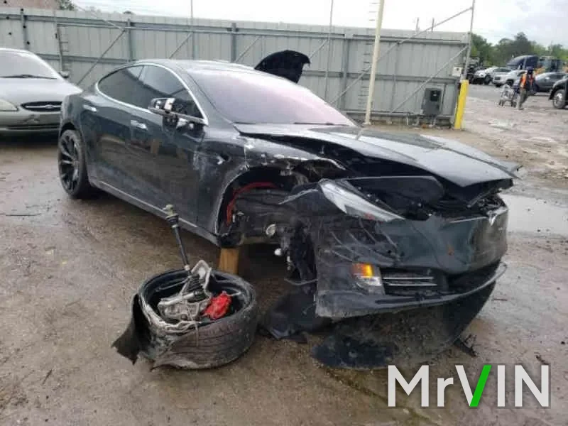 A Tesla Model S with its front wheel torn off at a salvage yard